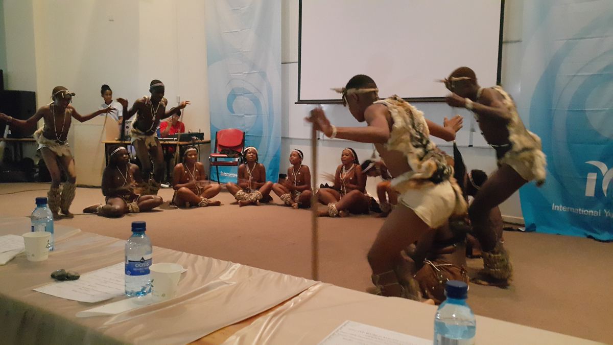 Dancers performing in traditional costume in a meeting room.