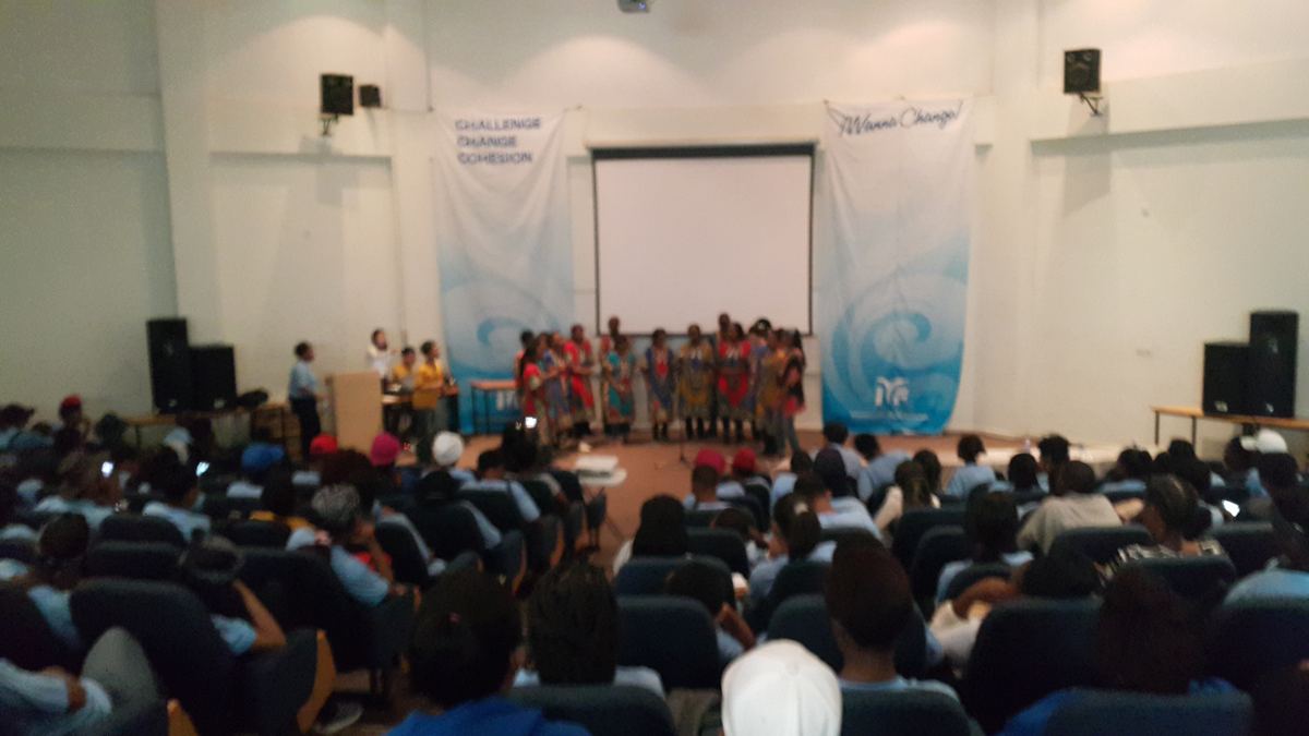 A hall full of young people watching a choir.
