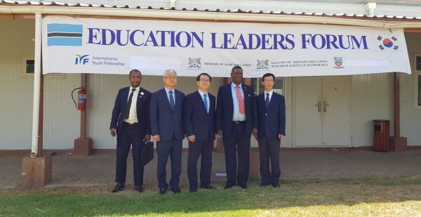 Delegates standing under an Education Leaders Forum banner.