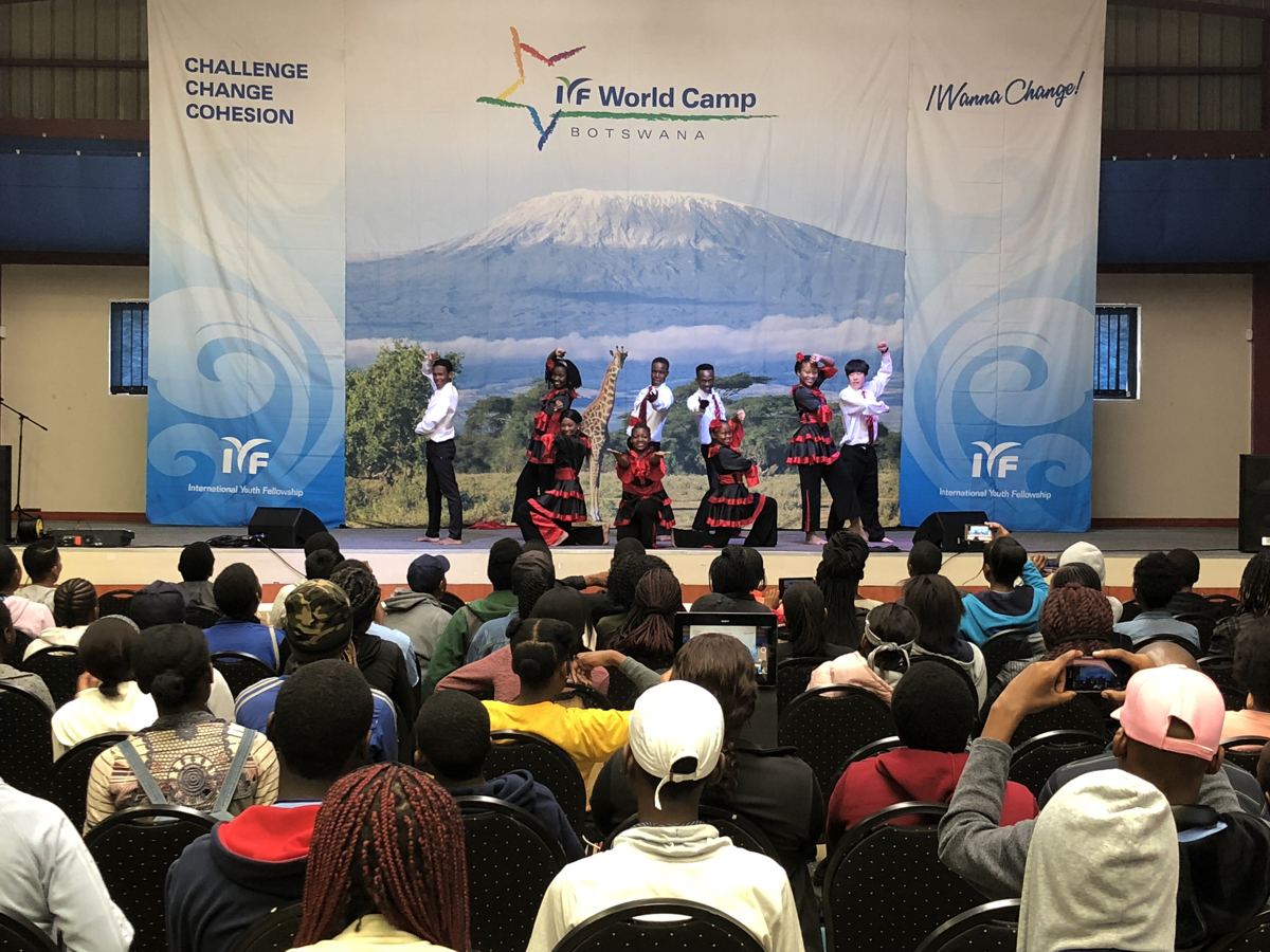 A dance troupe performing on stage under the World Camp backdrop.