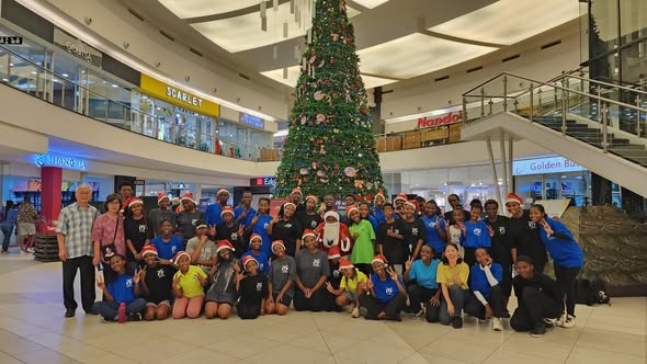 IYF members gathered in front of a large Christmas tree in a shopping mall.